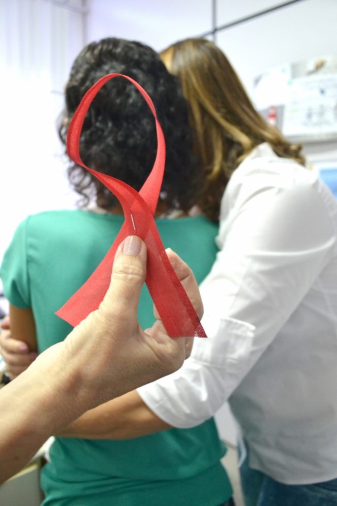 Fita símbolo da aids é exposta à frente de duas pessoas